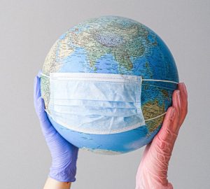 hands with latex gloves holding a globe with a face mask